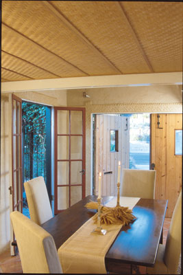 In the garage-turned-dining/family room, Kelly tried out many of the systems and finishes she planned to use later in the rest of the house: hydronic radiant heating in a topping slab over the garage floor slab; saltillo tile flooring; earth-plastered walls with a decorative pattern pressed into trim bands; and a bamboo-mat ceiling. Salvaged French doors open onto the new front patio, and the swinging garage doors admit abundant fresh air and light when needed.